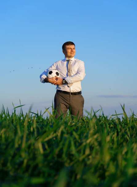 businessman poses with soccer ball in a green grass field - freelance, sport and business concept - Foto, imagen