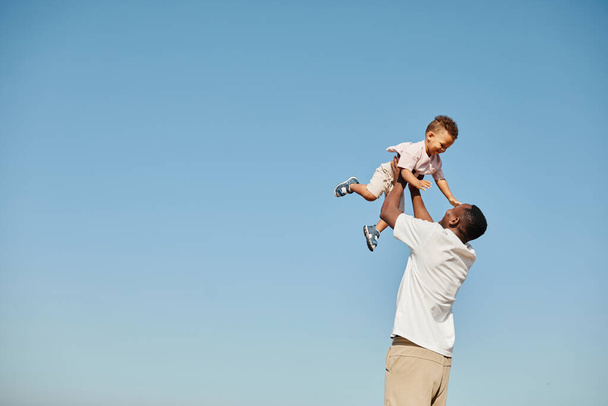 Afroamerykanin tata gra z synem przeciwko niebu - Zdjęcie, obraz