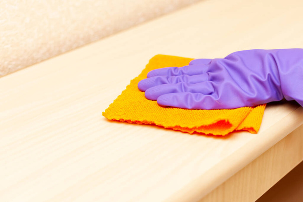 hand in a purple rubber glove wipes a wooden shelf close-up - Photo, Image