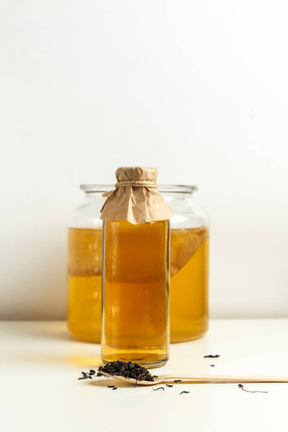 Sweet and sour carbonated Kombucha drink. Kombucha is a symbiotic culture of bacteria that metabolize sugar. The drink is ready in 5-10 days, it is drained and stored in the refrigerator.Vertical frame on a light background - Photo, Image
