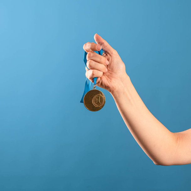 Win ,be a champion. Striving for achievements, concept, a female hand squeezes the winners gold medal, - Fotoğraf, Görsel