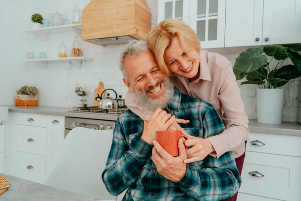 marido y mujer se abrazan en casa durante el desayuno - Foto, imagen