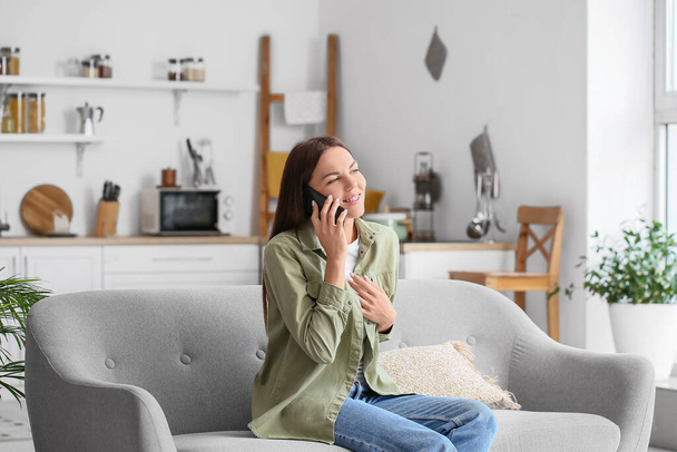 Νεαρή γυναίκα μιλάει στο τηλέφωνο στο σπίτι - Φωτογραφία, εικόνα