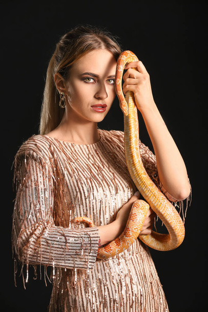 Сексуальная молодая женщина со змеей на черном фоне - Фото, изображение