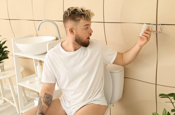 Šokovaný mladý muž z toaletního papíru v koupelně - Fotografie, Obrázek