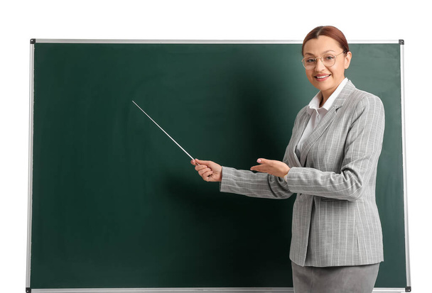 Portret van vrouwelijke leraar in de buurt van schoolbord op witte achtergrond - Foto, afbeelding