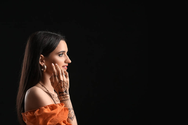 Beautiful Indian woman with henna tattoo on dark background - Photo, Image
