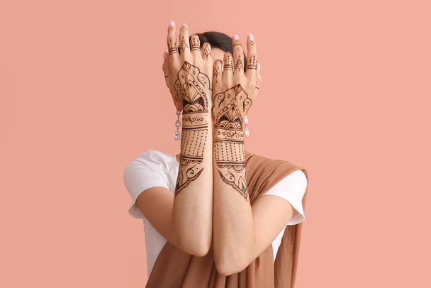 Beautiful Indian woman with henna tattoo on color background - Photo, Image