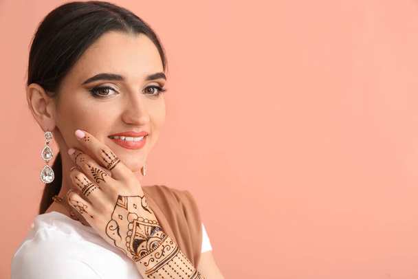 Beautiful Indian woman with henna tattoo on color background - Фото, зображення