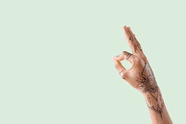 Female hand with henna tattoo on color background - Foto, afbeelding