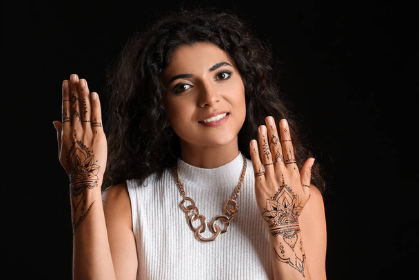 Beautiful Indian woman with henna tattoo on dark background - Fotoğraf, Görsel