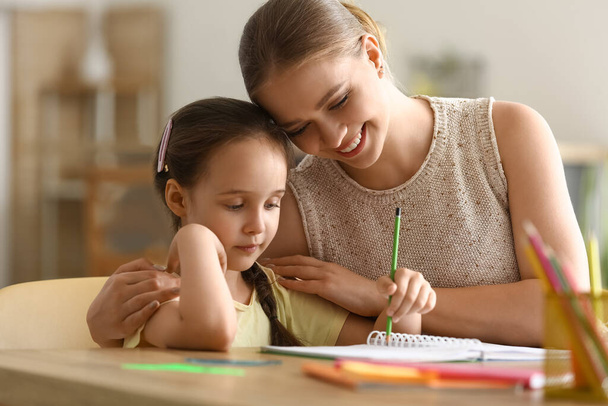 Little girl with her mother doing lessons at home - Foto, Imagen