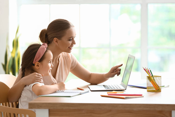 Kleines Mädchen mit ihrer Mutter beim Online-Unterricht zu Hause - Foto, Bild