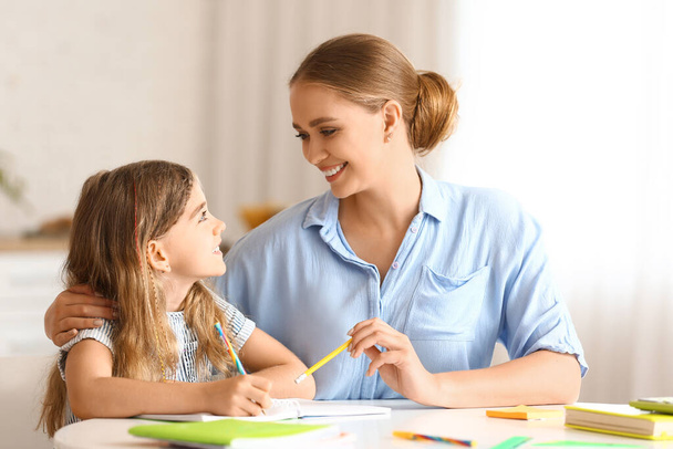 Niña con su madre haciendo clases en casa - Foto, Imagen