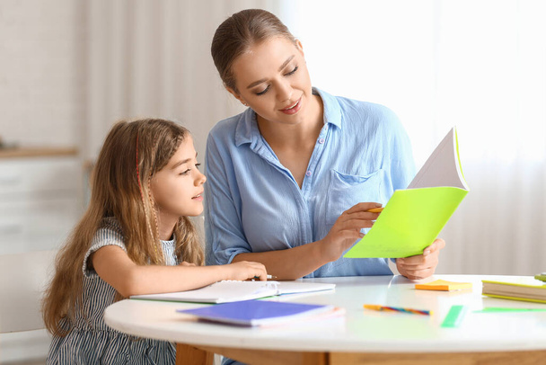 Niña con su madre haciendo clases en casa - Foto, Imagen