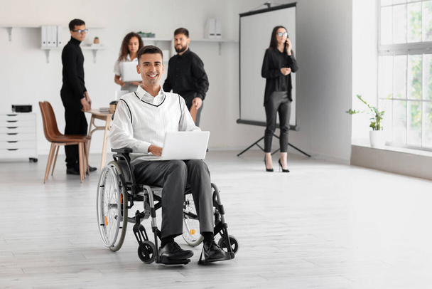 Man in wheelchair with laptop in office - Photo, Image