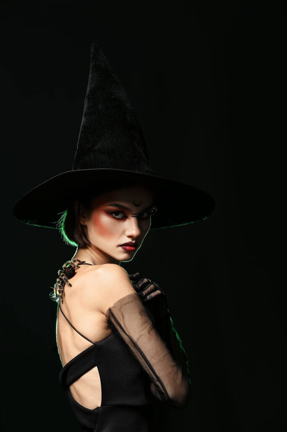 Young witch with spider on dark background - Photo, Image