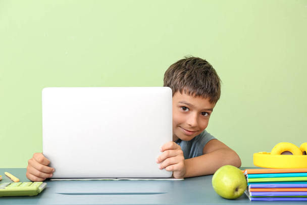 Little boy with laptop at table on color background - Photo, Image