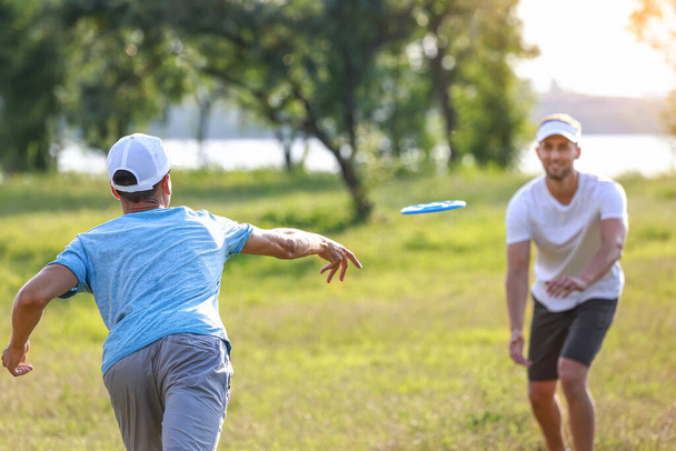 Young men playing frisbee in park - Photo, Image