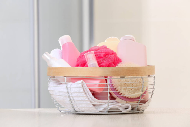 Basket with bath supplies on table in room - Фото, изображение