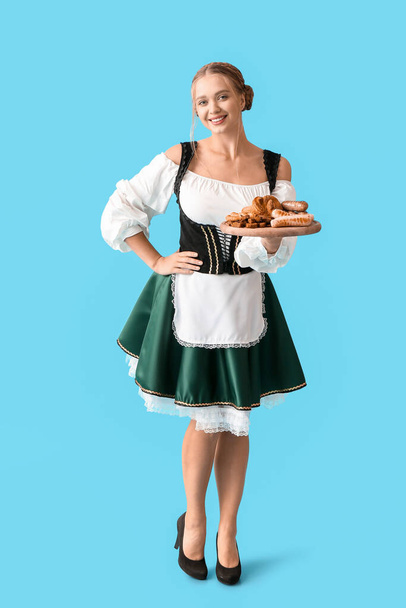 Гарна жінка в традиційному німецькому костюмі і з перекусками на кольоровому фоні - Фото, зображення