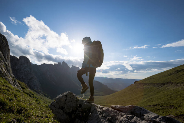 Successful woman backpacker hiking on sunset alpine mountain peak - Fotografie, Obrázek