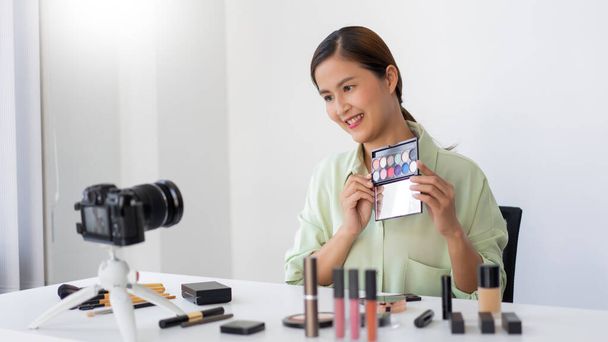 Женщина-блоггер красоты рассматривает качество красочной палитры теней для век в качестве нового продукта прибытия. - Фото, изображение