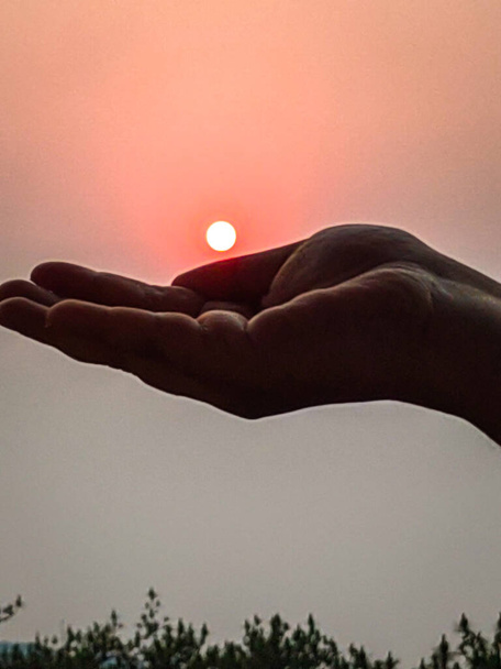 sunset through hand and finger shape at sunset from flat angle - Valokuva, kuva