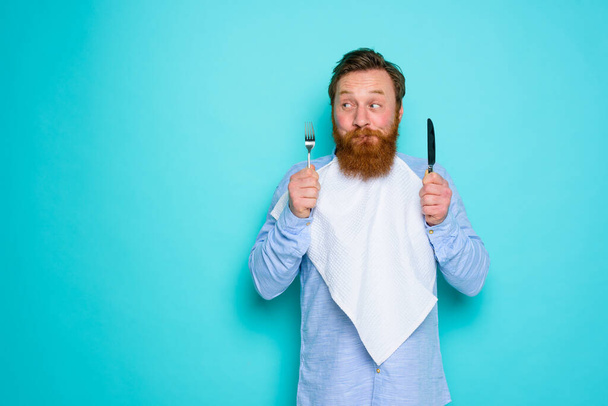Man with tattoos is ready to eat with cutlery in hand - Foto, Imagem