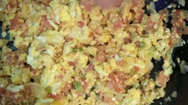 Top view of a hand sprinkling salt over Mexican-style scrambled eggs - Footage, Video