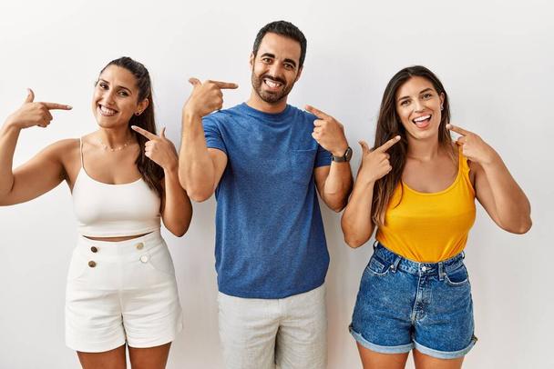 Groep jonge Latijns-Amerikaanse mensen staan over geïsoleerde achtergrond glimlachend vrolijk tonen en wijzen met vingers tanden en mond. tandheelkundige gezondheidszorg.  - Foto, afbeelding