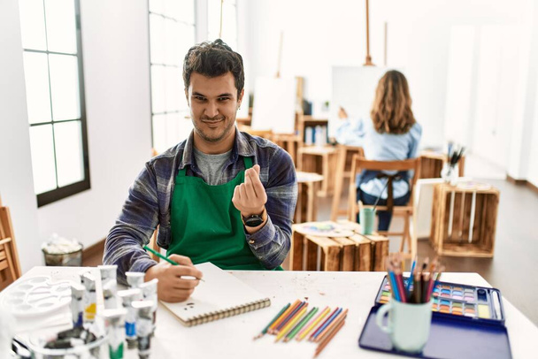 Jeune artiste homme au studio d'art faisant geste d'argent avec les mains, demandant le paiement du salaire, entreprise millionnaire  - Photo, image