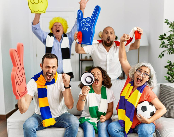 Grupo de amigos de meia-idade assistindo e apoiando jogo de futebol em casa. - Foto, Imagem