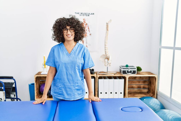 Fiatal közel-keleti nő visel fizikoterapeuta egyenruhát áll a klinikán - Fotó, kép