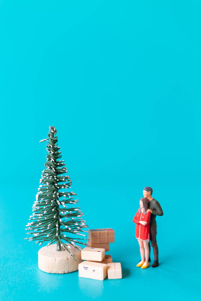 Miniaturowi ludzie, zakochana para stojąca obok choinki, Boże Narodzenie i Szczęśliwego Nowego Roku. - Zdjęcie, obraz