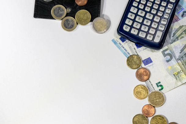 Europäisches Geld mit schwarzer Brieftasche auf weißem Schreibtisch als weißer Hintergrund mit verschiedenen Euro-Münzen und Euro-Banknoten mit Rechner für Finanzmanagement und Einkommenspläne zur Steuerberechnung - Foto, Bild