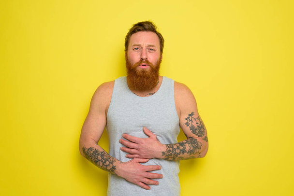 El hombre que sufre con barba y tatuajes tiene dolor de estómago - Foto, Imagen