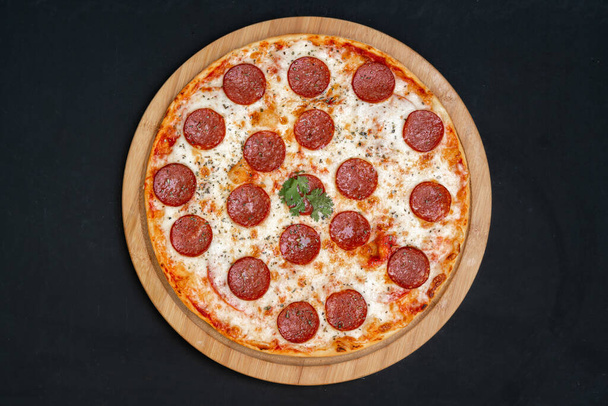 Pizza pepperoni, mozzarella, oregano on a black background - Фото, зображення