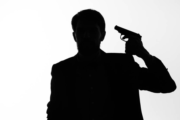 Mies puvussa ase käsissä tunteita siluetti poseeraa studio - Valokuva, kuva