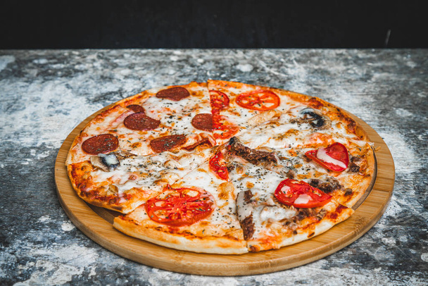 Slices of italian pizza on abstract dark background with wheat flour - Φωτογραφία, εικόνα