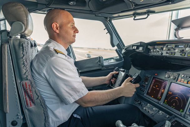 Уверенный пилот сидит в кабине и держит руль - Фото, изображение