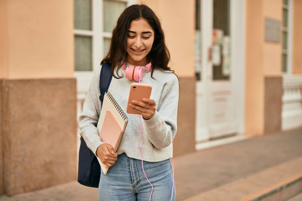 Nuori Lähi-idän opiskelija tyttö hymyilee onnellinen käyttäen älypuhelin kaupungin. - Valokuva, kuva