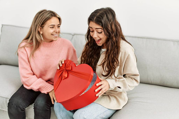 Молода жінка дивує свою дівчину валентинковим подарунком вдома
. - Фото, зображення