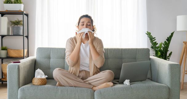 Ill upset girl is holding paper tissue and blowing nose. Virus symptom concept. - Foto, Imagen
