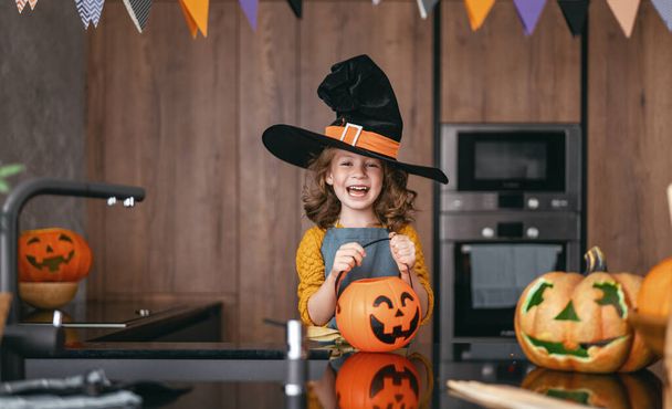 Cute little child girl with carving pumpkin. Happy family preparing for Halloween.  - Fotó, kép
