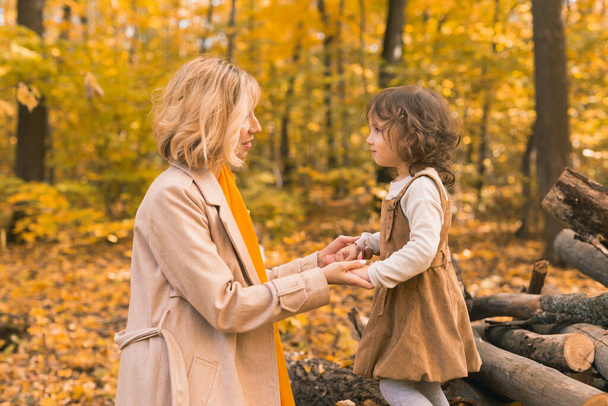 Mother and little daughter enjoying nice autumn day in a park. Season, family and children concept. - 写真・画像