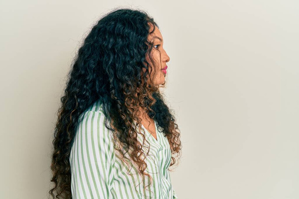 Junge lateinamerikanische Frau trägt lässige Kleidung, die zur Seite schaut, entspannte Profilpose mit natürlichem Gesicht und selbstbewusstem Lächeln.  - Foto, Bild