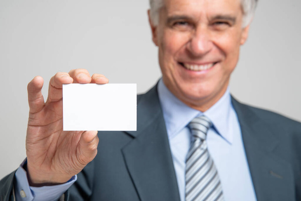 Senior businessman showing a business card, covid or coronavirus concept - 写真・画像