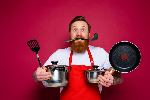 испуганный шеф-повар с бородой и красным фартуком готов готовить - Фото, изображение