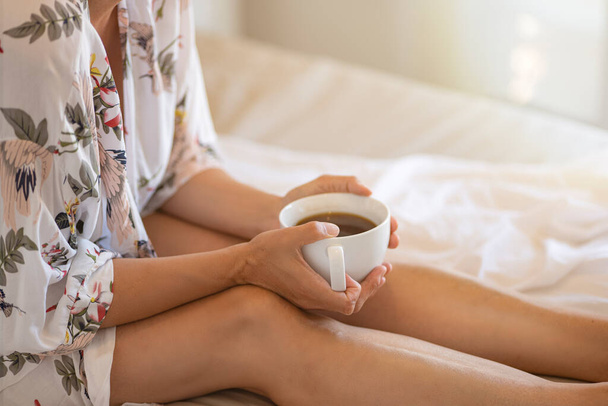 close up of young woman with cup of coffee in bed at home - Photo, Image